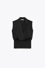 Top sin mangas de tejido piqué color gris oscuro, con diseño cruzado tipo solapa en el escote y detalle de pliegues en la parte delantera. Presenta un elástico ancho en la cintura.