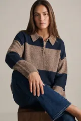 Sweater de punto con cuello polo y cierre frontal de tres botones. Presenta un diseño de corte oversize, mangas largas y textura acanalada.