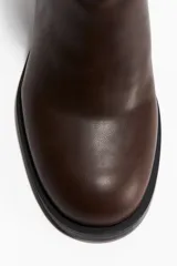 Botines de caña media en color marrón oscuro, con punta redonda, diseño de costuras visibles en el lateral y taco cuadrado de altura media.