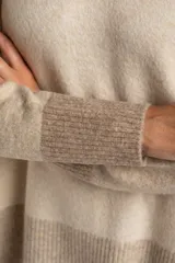 Sweater de tejido de punto con diseño color block. Cuerpo principal en beige jaspeado, mangas y puños en azul marino, y detalles en marrón en el cuello y puños.