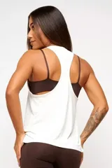 Musculosa deportiva blanca de corte holgado, con espalda estilo nadador y logo pequeño en el ruedo.