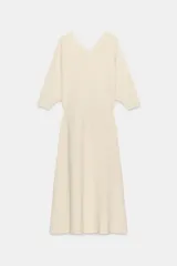 Vestido midi de punto color marfil con escote en V, mangas largas de sisa ancha, cintura entallada y falda de corte evasé.