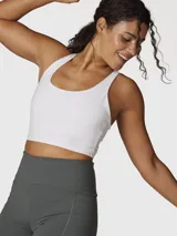 Top deportivo blanco de sujeción media con espalda cruzada, confeccionado con tecnología Aloe Vera para una textura suave y elástica.