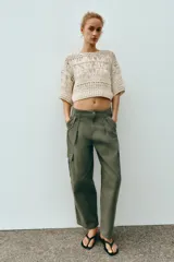 Top cropped de punto con diseño combinado de texturas, cuello redondo y mangas cortas amplias. Presenta una estructura calada con detalles de cintas verticales.