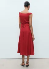 Vestido midi de corte evasé confeccionado en mezcla de lino y lyocell. Presenta escote barco, tirantes anchos y cierre frontal con botones a tono. Incluye detalle de lazo en la parte posterior.