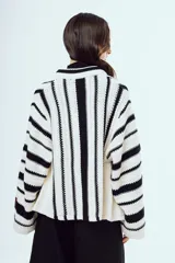 Cardigan de punto a rayas verticales blancas y negras, con mangas largas amplias y diseño abierto al frente.