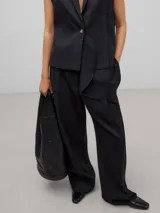 Pantalón de pierna ancha y cintura alta, confeccionado en una mezcla de lana merino, poliéster y viscosa. Presenta bolsillos laterales y bolsillos de vivo en la parte trasera.