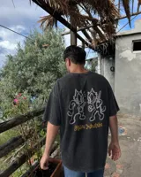 Remera marrón oversize de manga corta con estampado gráfico en la espalda de dos gatos de estilo retro con cuchillos y texto "Kahoa Industries".