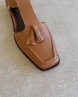 Mocasín negro de cuero vacuno, con punta cuadrada y detalle de borlas en el empeine.