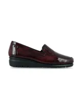 Zapato mocasín slip-on de cuero charol color bordó, con suela anatómica negra en contraste y diseño atemporal.
