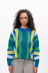 Buzo de tejido de punto con diseño de rayas verticales onduladas en tonos azul, verde, lima y celeste. Presenta cuello redondo y puños acanalados.