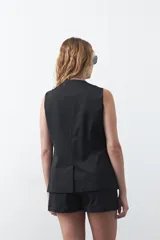 Chaleco sastrero de color marrón, con silueta recta, escote en V y cierre frontal con botones. Presenta una estructura definida y tejido con caída firme.