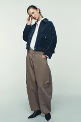 Cazadora estilo bomber confeccionada en piel, con cuello solapa, manga larga y cierre frontal con cremallera oculta y botones a presión. Presenta bolsillos delanteros de plastrón con solapa y botón a presión.