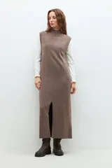 Vestido midi tejido color chocolate, de corte recto, cuello alto y sin mangas. Presenta un tajo frontal.