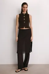 Falda pantalón de tiro alto en color marrón oscuro, con diseño de superposición que combina un pantalón recto con una falda envolvente con lazadas laterales. Cuenta con cierre lateral oculto.