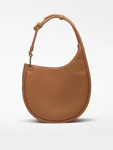 Bolso hobo color marrón claro, con textura napa y asa tubular con pieza metálica. Tiene un compartimento con cierre de clip magnético y un bolsillo interior con cremallera.