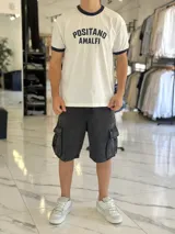 Remera de algodón pesado de corte oversize en color blanco, con cuello redondo y ribetes en las mangas de color azul marino. Cuenta con un estampado frontal con el texto "POSITANO AMALFI".