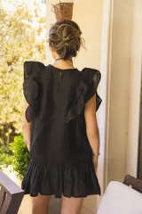 Blusa negra de lino con volados en los hombros y pespuntes en color beige.