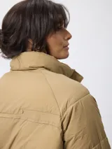 Campera puffer de nylon color negro, con cuello alto, cierre frontal con cremallera y botones a presión. Presenta bolsillos frontales con solapa y diseño acolchado.