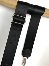 Correa ajustable para cartera confeccionada en cinta tejida con diseño de rayas en negro, blanco y beige, con punteras de cuero sintético negro y herrajes metálicos.