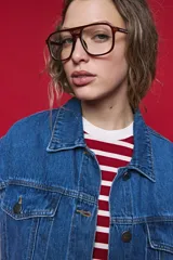 Chaleco de jean azul con corte oversized, cuello camisero, bolsillos delanteros y cierre frontal con botones metálicos.
