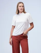 Blusa de cuello alto con torso en tejido crepe liso y mangas cortas abullonadas confeccionadas en encaje floral. Presenta un diseño elegante y versátil.