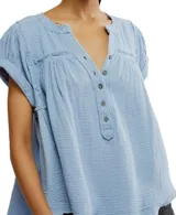 Camisa de doble gasa de algodón color celeste, con cuello en V, cierre frontal parcial con botones y mangas cortas holgadas.
