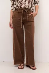 Jean tostado de corte wide leg, tiro medio con presillas y lazo ajustable en la cintura. Presenta bolsillos delanteros y traseros, costuras decorativas verticales y terminación desmechada en el ruedo.