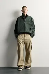 Cazadora relaxed fit de denim de algodón color verde oscuro, con cuello subido y cierre de cremallera frontal. Cuenta con bolsillos de vivo con solapa en la cadera, acabados elásticos y detalle bordado a contraste en el pecho.