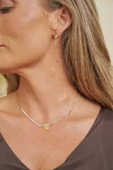 Gargantilla de acero dorado con circonias engastadas en gran parte de su longitud y un dije colgante en forma de corazón dorado.