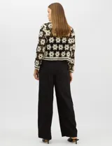 Cardigan abierto de tejido crochet con diseño de flores bicolores en negro y crema. Presenta mangas largas, frente abierto sin cierre y bolsillos frontales tipo parche. Posee terminaciones con franjas a contraste en escote, puños y ruedo.