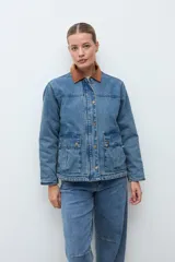 Campera de jean en tono azul medio, con cuello de pana en color marrón, cierre frontal con botones metálicos y bolsillos frontales tipo cargo.