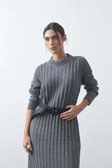 Vestido midi de punto en color gris, con diseño de tejido acanalado vertical, cuello redondo y mangas largas. Presenta una silueta recta y fluida.