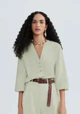 Blusa verde a rayas verticales con cuello en V y cierre frontal con botones. Mangas 3/4 y corte holgado.