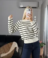 Sweater de punto con diseño de rayas horizontales negras sobre fondo blanco, cuello redondo y puños y ruedo acanalados.