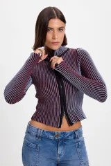 Campera corta de tejido de punto acanalado con diseño de rayas verticales en dos tonos. Presenta cuello alto y cierre frontal completo con borde en color negro.