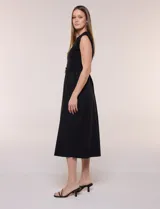 Vestido midi negro con torso de jersey sin mangas y falda de algodón, corte en la cintura con lazo de ajuste y hebilla metálica triangular.