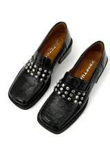 Mocasín de cuero charol negro con detalle de apliques metálicos plateados en la parte delantera y taco bajo cuadrado.