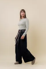 Pantalón wide leg de tiro alto en color negro, con diseño de pinzas delanteras que aportan volumen y caída fluida. Incluye bolsillos laterales y un lazo desmontable en la cintura que combina cordón con cinta de estampado animal print.