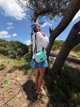 Bandolera pequeña de diseño moderno, confeccionada en tafeta liviana y resistente. Cuenta con cierre superior, correa ancha ajustable y logo frontal de la marca.