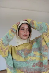 Capucha tejida a mano en lana merino con diseño de rayas horizontales en color mostaza y beige. Presenta una forma envolvente con lazos largos para anudar bajo el cuello, funcionando como un accesorio independiente de abrigo.