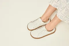Zapatillas de cuero blanco con diseño minimalista, cordones al tono y suela de goma color suela con costura vista.