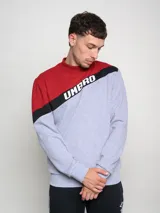 Buzo de hombre con diseño de bloques de color, combinando rojo en la parte superior de los hombros y gris melange en el cuerpo. Presenta una franja diagonal negra con el logo Umbro en blanco cruzando el pecho.