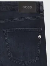Jean de corte slim-fit en denim azul oscuro con efecto desgastado, cierre de botón y cremallera, y diseño de cinco bolsillos.