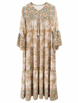 Vestido largo color tostado con estampado estilo paisley y floral en tonos blancos y turquesas, mangas largas acampanadas y cordón ajustable en el cuello con borlas colgantes.