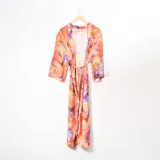 Kimono largo con estampado de hojas en tonos naranja y violeta, con mangas anchas y lazo para ajustar en la cintura.