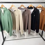 Sweater de punto verde con cuello polo y cierre de cremallera parcial.