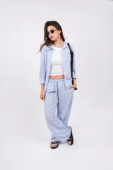 Pantalón largo de mujer, de corte amplio y tiro alto, con estampado a rayas verticales en tonos beige y blanco. Tiene cintura elástica con cordón ajustable.