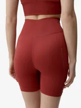 Short deportivo de tejido seamless en color rojo, tiro alto y diseño ajustado con detalles de perforaciones laterales y pequeño logo reflectante.