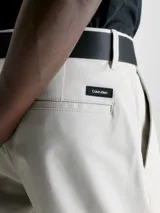 Shorts color crema de sarga de algodón orgánico con elasticidad añadida, talle medio, bragueta con cremallera, bolsillos laterales y traseros, cinturón con hebilla en forma de D incluido y micrologo de Calvin Klein.